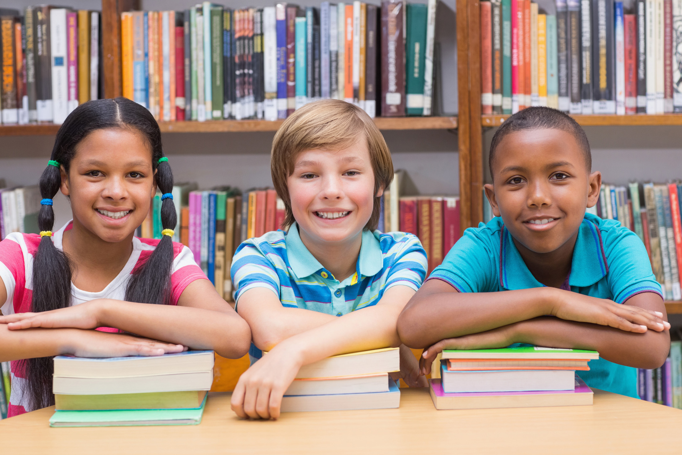 Cute pupils looking at camera in library at the elementary school